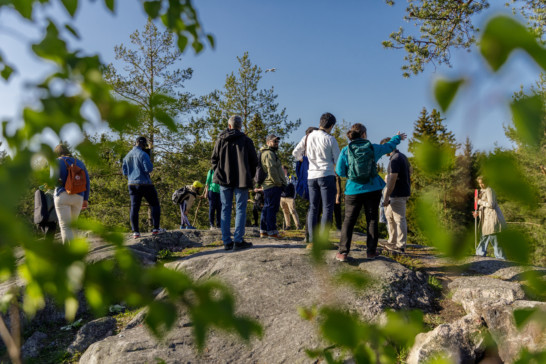 Ryhmä ihmisiä kallion huipulla aurinkoisena päivänä