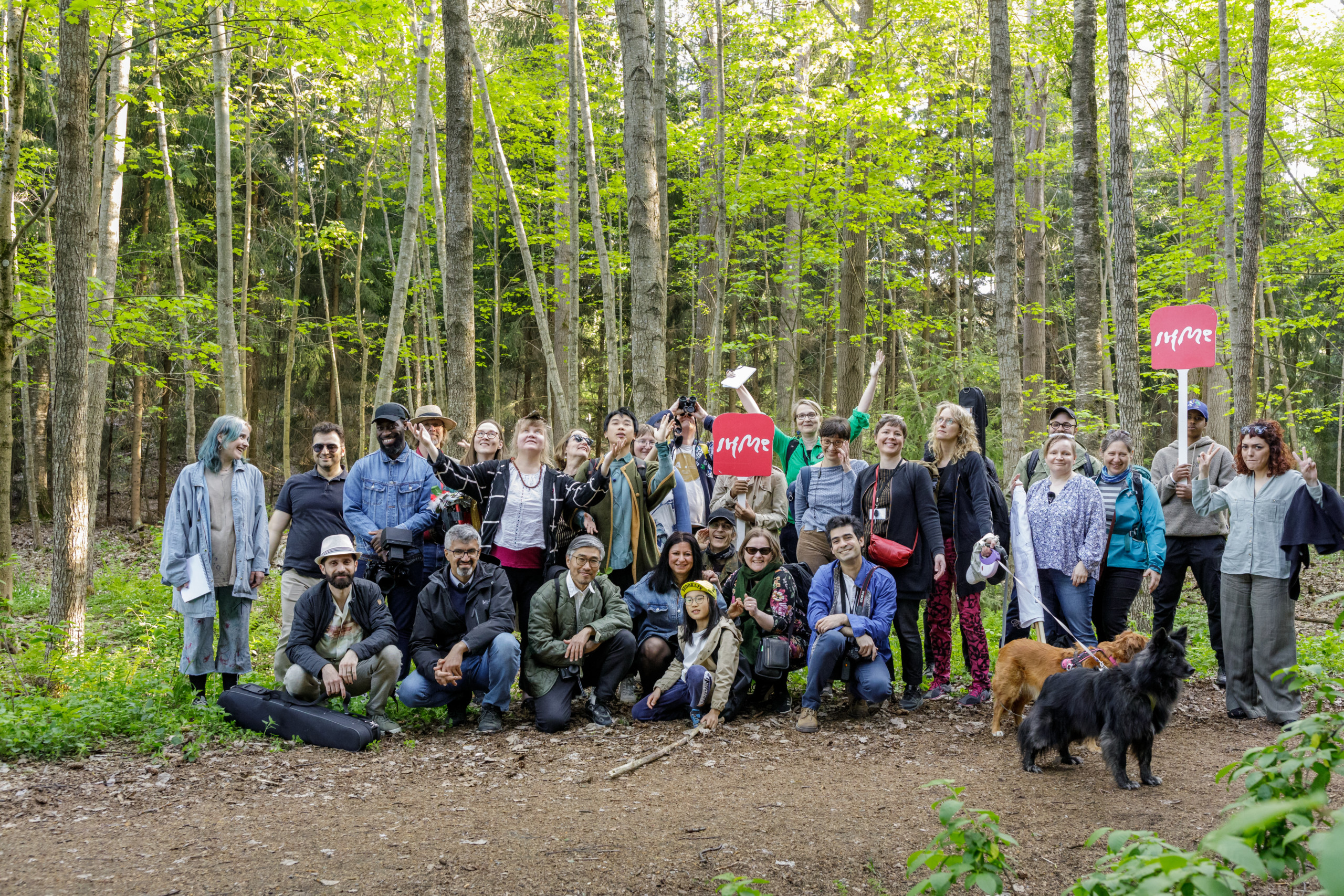 Ryhmä ihmisiä hymyilee metsässä.
