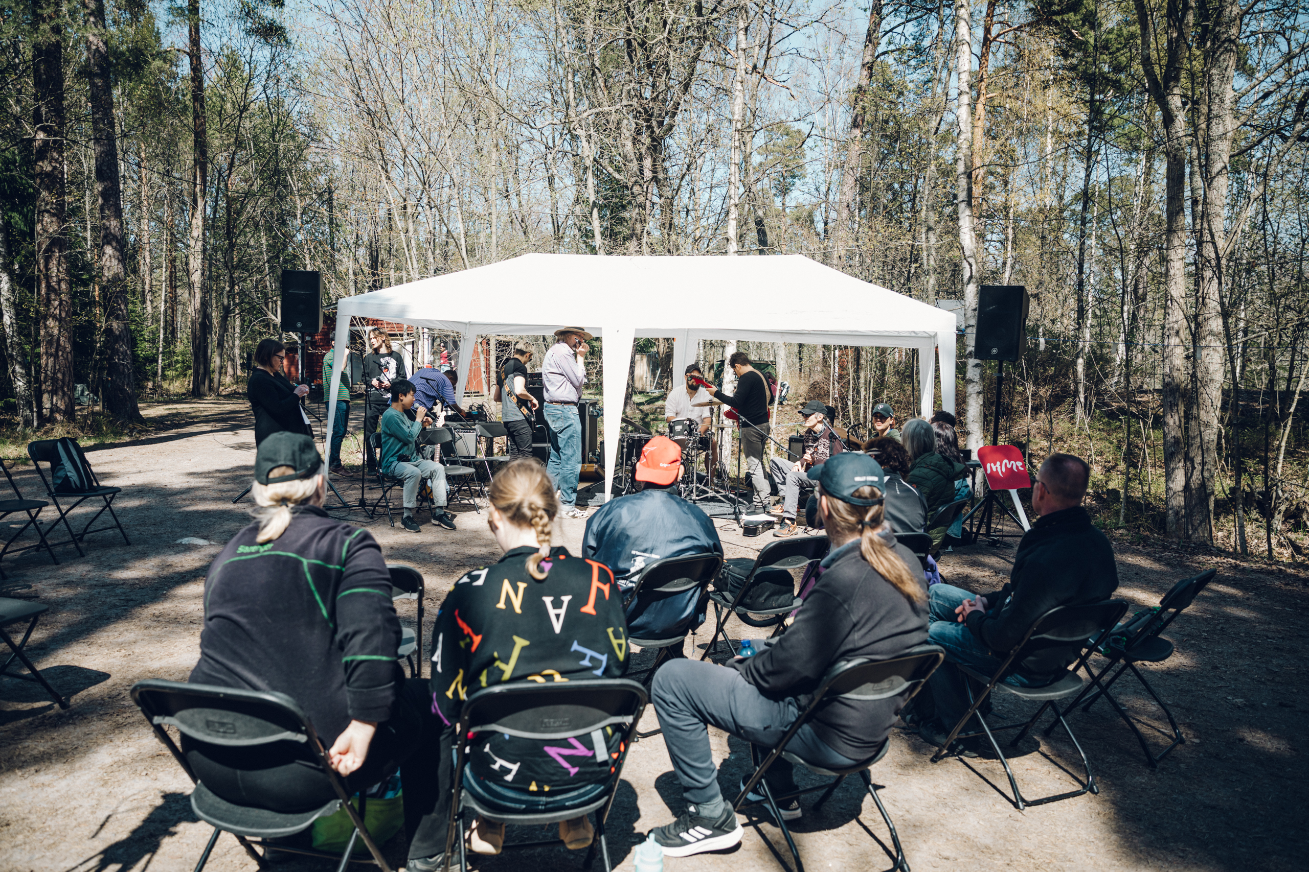 Ihmisiä ulkona soittamassa musiikkia ja kuuntelemassa.