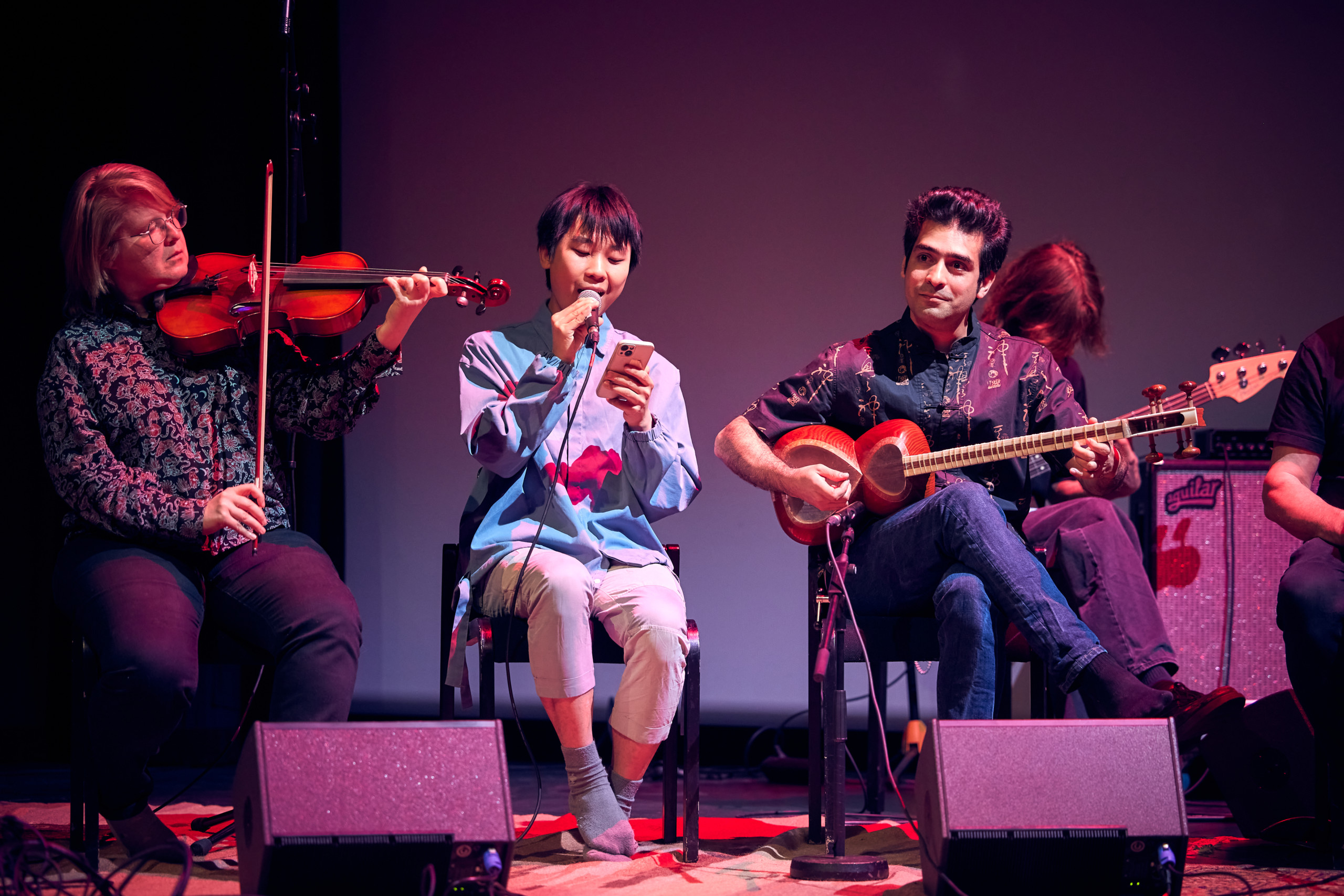 One person playing a viola, one person singing and one person playing tar.