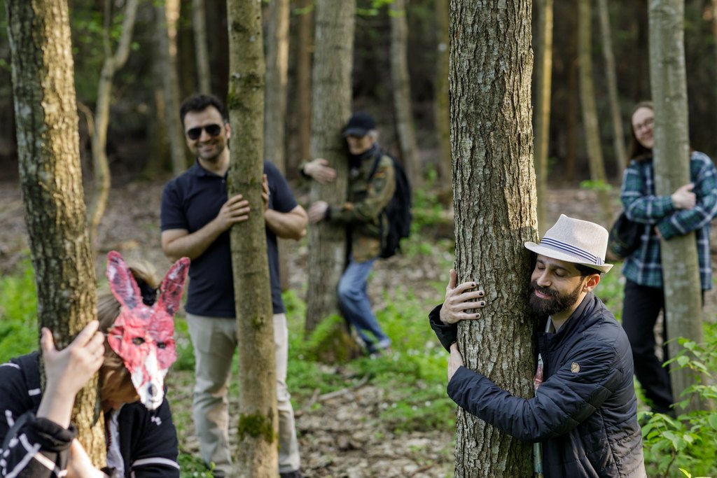 A group of people in forest hugging trees during spring time.