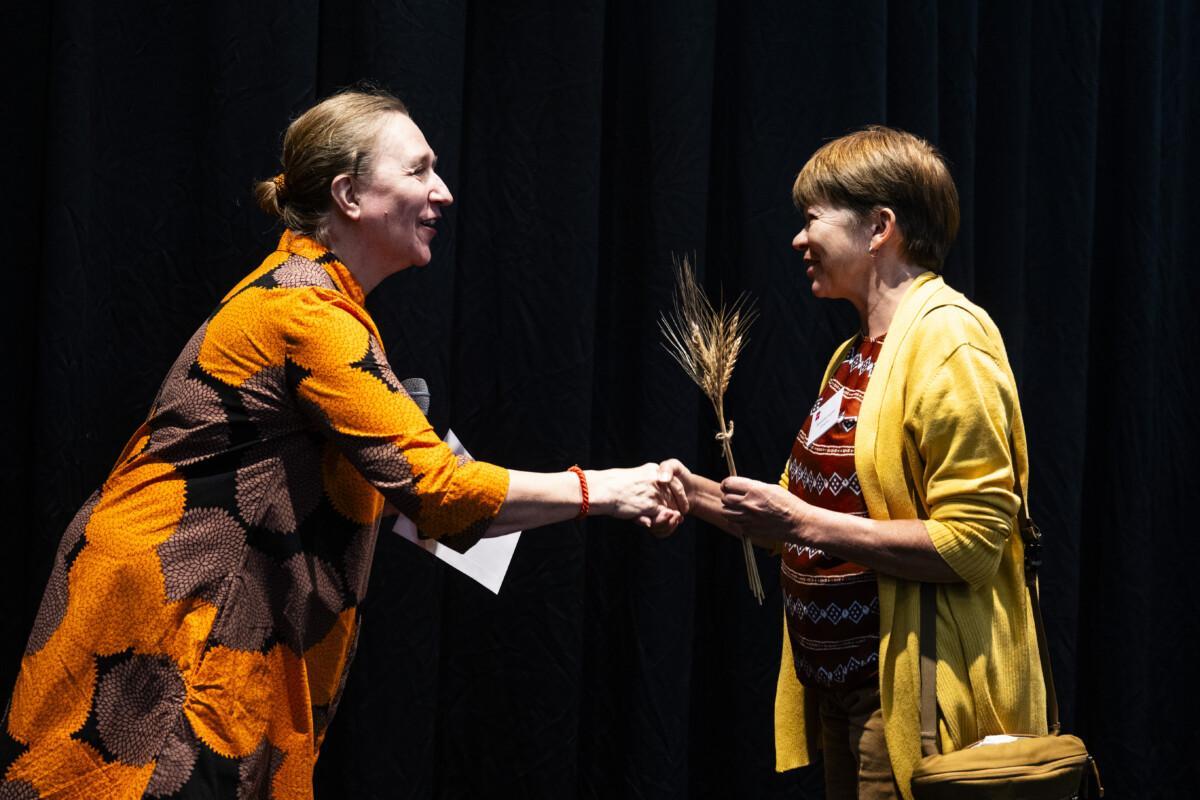 The picture shows two people dressed in yellow, happily shaking hands.