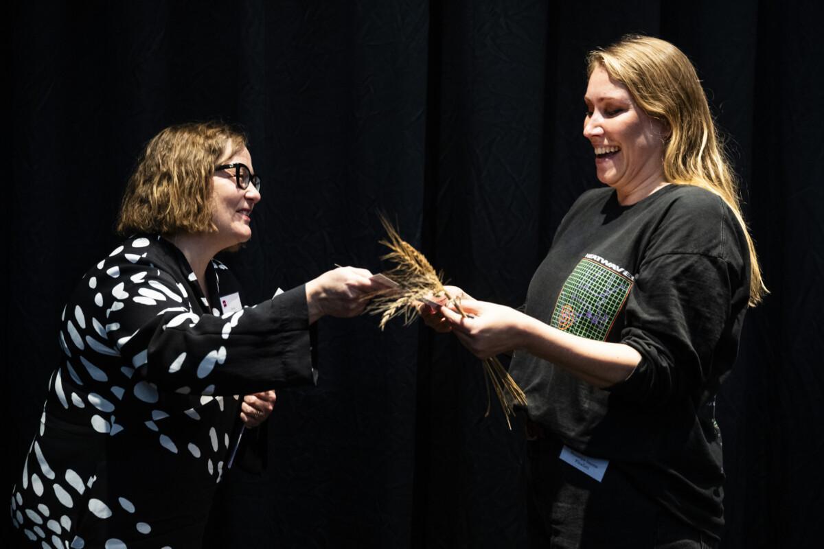 The picture shows two people dressed in black, happily shaking hands.